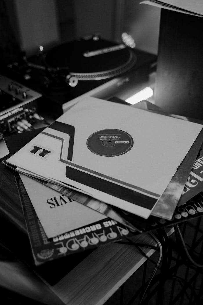 Black and white photo of stacked vinyl records beside a turntable in retro setup.